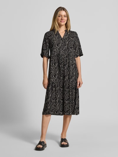 Frauenmodel trägt Ausgestelltes Maxikleid aus reiner Viskose Modell 'EASY JOY' von Vero Moda mit Allover-Muster in Schwarz, Ganzkörperansicht von vorne.
