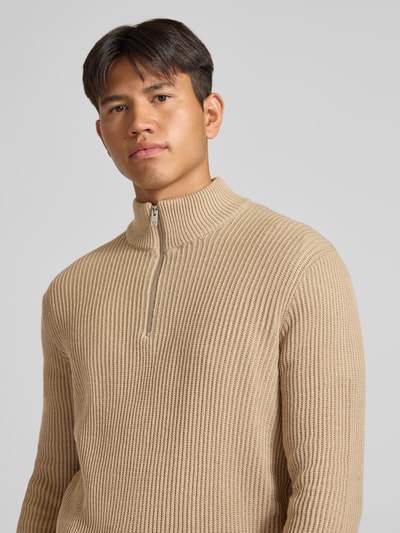 Männermodel trägt Strickpullover mit Troyer-Kragen Modell 'PANNEL' von JACK & JONES, beige, Rippenstruktur, Nahaufnahme Oberkörper, Material-Mix mit Baumwoll-Anteil, eng anliegender Schnitt.