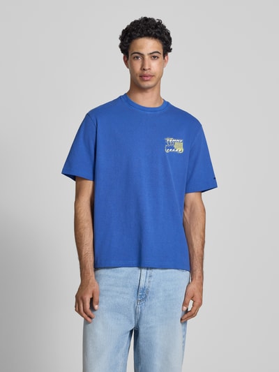 Männermodel trägt Regular Fit T-Shirt aus reiner Baumwolle Modell '90s' von Tommy Jeans, Optik: Unifarben, Label-Print, Rundhals, Kurzarm, Materialverarbeitung: Jersey, Ganzkörperansicht von vorne.
