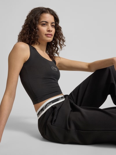 Frauenmodel trägt Slim Fit Top mit Logo-Print von ANOTHER COTTON LAB in Schwarz, aus elastischem Baumwoll-Mix, Nahaufnahme Oberkörper.