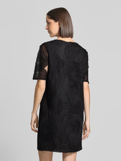 Vrouwenmodel draagt zwart Relaxed Fit vrijetijdsjurk met structuurpatroon van s.Oliver BLACK LABEL, rugaanzicht hele lichaam.