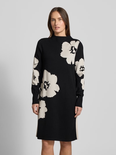 Vrouwenmodel draagt Relaxed Fit Jurk uit viscosemix in tricotlook van Betty Barclay, gebloemd, knielengte, met lange mouwen, opstaande kraag, elastische mouwboord, zwarte en beige tinten, bloemenmotief, geheelvoorzicht.