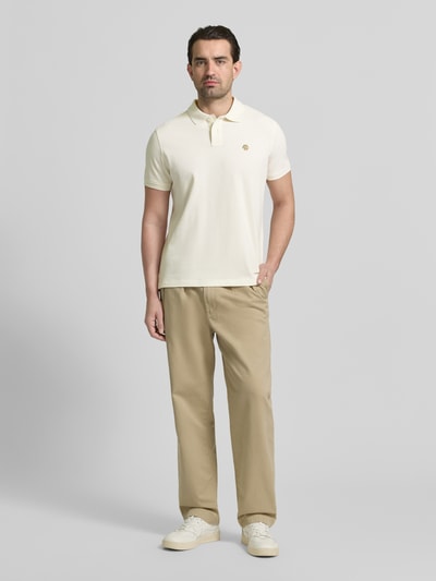 Männermodel trägt Slim Fit Poloshirt mit Logo-Stitching von MCNEAL in Creme, reine Baumwolle, Polokragen, Ganzkörperansicht von vorne.
