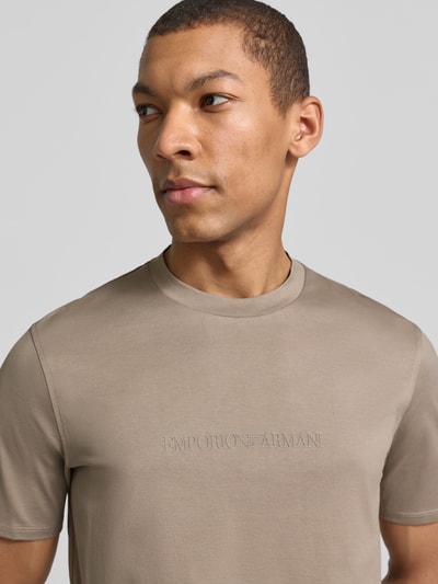 Männermodel trägt Regular Fit T-Shirt mit Logo-Detail von Emporio Armani in Beige, reine Baumwolle, Rundhalsausschnitt, Nahaufnahme Oberkörper.