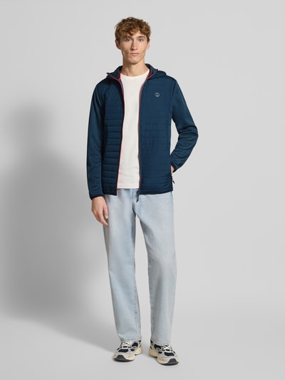 Männermodel trägt Steppjacke mit Reißverschluss Modell 'MULTI QUILTED JACKET' von JACK & JONES, Regular-Fit, Kapuze, Label-Print, Ganzkörperansicht von vorne.