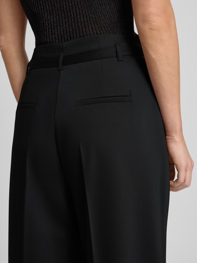 Frauenmodel trägt Stoffhose mit Gesäßtaschen von More & More, schwarzer Material-Mix, lockerer Schnitt, Nahaufnahme Rückansicht