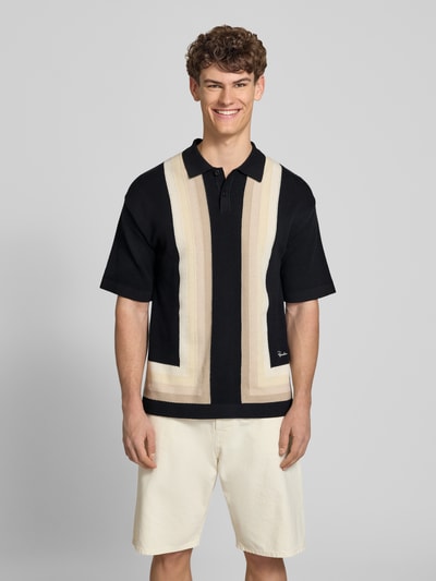 Męski model nosi koszulkę polo Relaxed Fit Poloshirt in Strick-Optik Modell 'Tellero' od Pegador z bawełny, imitacja dzianiny, krój relaxed fit, z krótkim rękawem, kołnierzyk polo, długość tyłu w rozmiarze M: 73 cm, kolor czarny z beżowymi i kremowymi akcentami, przód, ujęcie całej sylwetki.