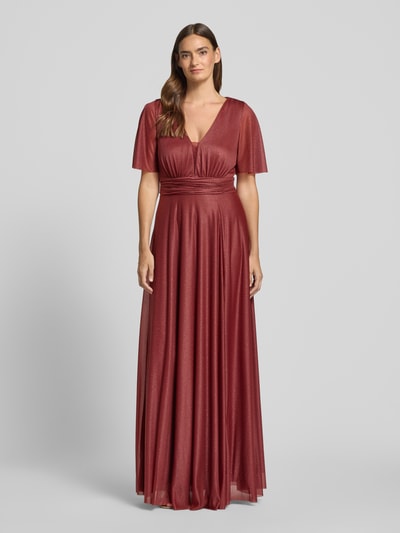 Modelka nosi 'Schimmerndes Maxikleid mit V-Ausschnitt und Taillenband' od Christian Berg Cocktail, siateczka, krój o linii a, efekt błyszczący, dekolt w serek, tasiemka w talii, długość tyłu w rozmiarze 36: 149 cm, szerokość klatki piersiowej w rozmiarze 36: 35 cm, długość rękawów w rozmiarze 36: 29 cm, całość w odcieniach czerwieni, widoczne delikatne marszczenia, tekstura lekko prześwitująca, gładka powierzchnia materiału, pełny widok sylwetki z przodu