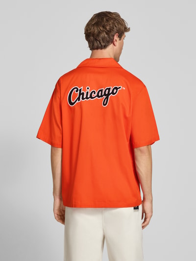Männermodel trägt Relaxed Fit Freizeithemd aus Baumwoll-Mix von Champion in Orange mit Statement-Stitching, Rückenansicht, Kurzarm, KI-modifiziertes Bild.