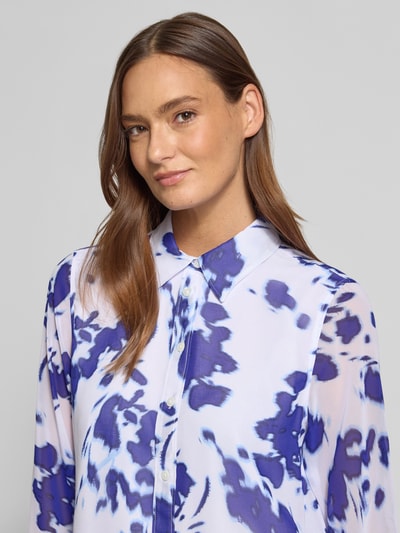 Vrouwenmodel draagt Regular Fit Hemdbluse in semitransparant design van Calvin Klein Womenswear, Chiffon, overhemkraag, met lange mouwen, doorknoopsluiting, sportmanchet, ruglengte maat S 62 cm, mouwlengte maat S 60 cm, blauwe en witte tinten, vlekachtig patroon, gladde textuur. Nahaufnahme bovenlichaam.