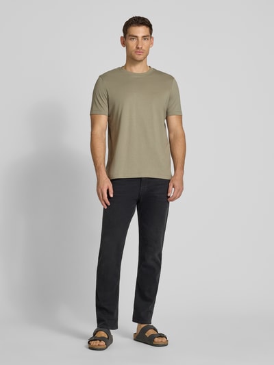 Męski model nosi Regular Fit T-Shirt aus reiner Baumwolle od s.Oliver RED LABEL w jednolitym kolorze, krój regular fit, krótki rękaw, okrągły dekolt, bawełniany dżersej, z nadrukiem z logo, widok całej sylwetki z przodu.