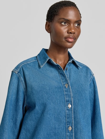 Frauenmodel trägt Relaxed Fit Jeansbluse mit Knopfleiste Modell 'CELIA' von Samsøe Samsøe, reine Baumwolle, mittleres Jeansblau, Nahaufnahme Oberkörper.