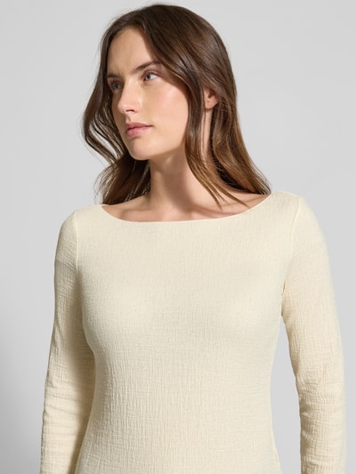 Frauenmodel trägt Slim Fit Longsleeve mit Viskose-Anteil von Emporio Armani in Creme mit Strukturmuster, Rundhalsausschnitt, Nahaufnahme Oberkörper.
