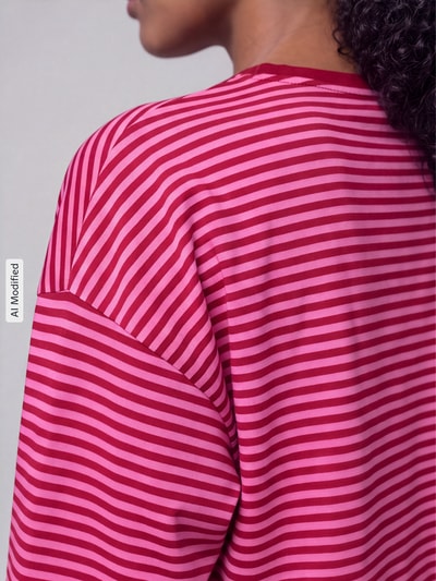Frauenmodel trägt Relaxed Fit Langarmshirt aus reiner Baumwolle Modell 'FREJA' von ONLY, pink-rot gestreift, Nahaufnahme Rückenansicht, Damen Langarmshirt von ONLY, KI-modifiziertes Bild.