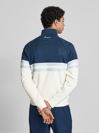Męskimodel nosi bluza rozpinana z mieszanki bawełny model 'RIMINI' od Ellesse, prosta forma, stójka, logo, wykończenia elastyczne, kolor granatowo-biały, długość tyłu 71 cm, długość rękawów 43 cm, całkowity widok z tyłu.