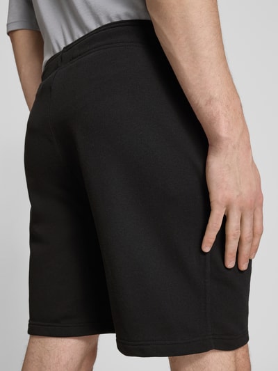 Männermodel trägt Shorts mit elastischem Bund und Label-Stitching von CHAMPION, katoenmix, regular fit, zwarte kleur, detailopname achterkant.