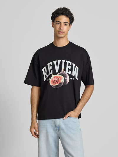 Männermodel trägt Relaxed Fit T-Shirt mit Logo-Print von REVIEW, schwarze Reine Baumwolle, Halbarm, Rundhalsausschnitt, Herren T-Shirt, Rückenlänge 68 cm, Ganzkörperansicht von vorne.