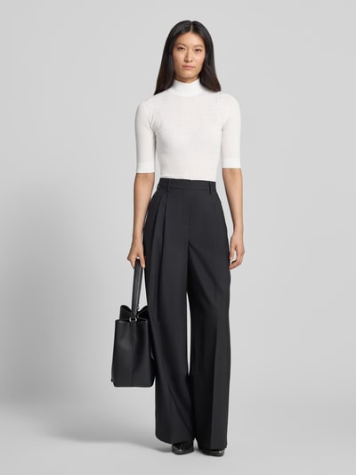 Frauenmodel trägt Slim Fit Longsleeve aus reiner Lanawolle Modell 'Maglia Costine' von Liu Jo White, weiß, halbarm, stehkragen, semitransparent, kombiniert mit schwarzer Hose, Ganzkörperansicht von vorne.