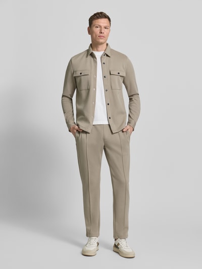 Männermodel trägt Sweatpants mit elastischem Bund von MCNEAL in Beige, Material-Mix mit Baumwoll-Anteil, lockerer Schnitt, Bundfalten, französische Eingrifftaschen und Gesäßtasche, Innenbeinlänge 75 cm bei Größe M, Ganzkörperansicht von vorne.
