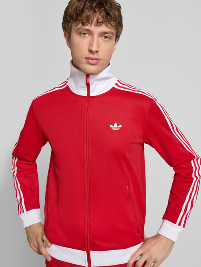 Männermodel trägt Regular Fit Sweatjacke mit Stehkragen Modell 'Classic' von adidas Originals, rot-weiß, Baumwoll-Mix, Nahaufnahme Oberkörper.