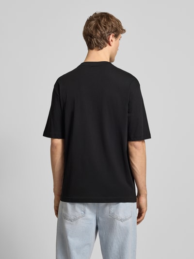 Męski model nosi Regular Fit T-Shirt aus reiner Baumwolle Modell 'NAMERIX' od Hugo Blue, efekt: jednolity kolor, krój regular fit, nadruk z logo, okrągły dekolt, krótki rękaw, czarna bawełna, widok całej sylwetki z tyłu.