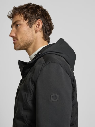 Männermodel trägt Regular Fit Steppjacke mit winddichter Funktion von Strellson, Schwarz mit matter Oberfläche, Nahaufnahme Oberkörper, Herren Steppjacke von Strellson.