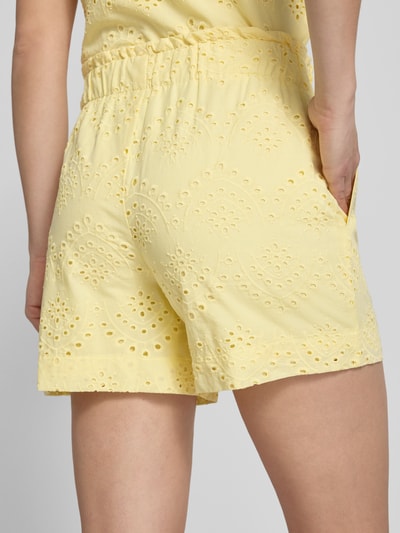 Frauenmodel trägt Loose Fit Bermudas mit Lochstickerei Modell 'VILDE' von Pieces in zartem Gelb, reine Baumwolle, seitliche Eingrifftaschen, elastischer Bund, unifarbene Optik, Detailaufnahme Rückansicht.