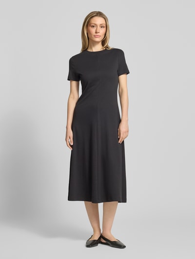 Frauenmodel trägt Midikleid aus reiner Baumwolle von Tommy Hilfiger in Unifarbe Schwarz, Regular Fit, Rundhals, kurzarm, Logo-Stitching, Ganzkörperansicht von vorne.
