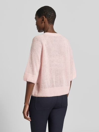 Männermodel trägt Regular Fit Cardigan aus Mohair-Alpaka-Mix in Strick-Optik von Marc Cain, zartrosa, strukturierte Textur, Ganzkörperansicht Rückansicht. Kontext: krój regular fit, okrągły dekolt, rękaw 1/2, zapięcie na guziki, długość tyłu w rozmiarze 36: 54 cm, długość rękawa w rozmiarze 36: 38 cm.