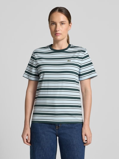 Frauenmodel trägt Regular Fit T-Shirt aus reiner Baumwolle von Lacoste mit grünen und weißen Streifen, Ganzkörperansicht von vorne, Damen T-Shirt von Lacoste.