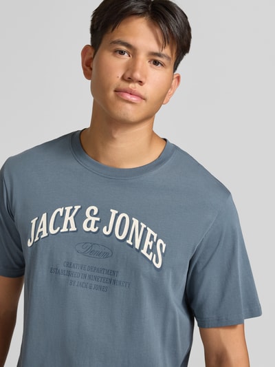 Männermodel trägt Regular Fit T-Shirt aus reiner Baumwolle Modell 'Denver' von JACK & JONES in Blau mit Logo-Print, Nahaufnahme Oberkörper.