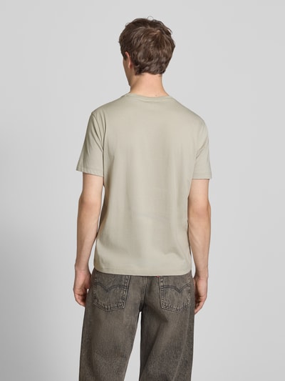 Männermodel trägt T-Shirt mit Label-Stitchings und Rundhalsausschnitt von CHAMPION in Beige, reine Baumwolle, Regular Fit, Ganzkörperansicht Rückansicht.