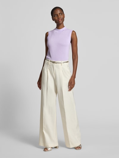 Frauenmodel trägt Stricktop aus Lyocell-Mix mit Rundhalsausschnitt Modell 'Remi' von GUIDO MARIA KRETSCHMER WOMAN, Slim Fit, Label-Detail, helllila fein gestrickt, kombiniert mit weiter cremefarbener Hose, Rückenlänge bei Größe 36: 50 cm, Ganzkörperansicht von vorne.