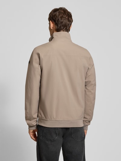 Männermodel trägt Regular Fit Jacke mit Stehkragen Modell 'Alvin' von Didriksons in Beige mit elastischen Abschlüssen, Ganzkörperansicht Rückansicht.