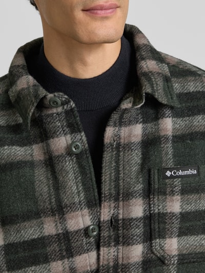 Männermodel trägt Regular Fit Freizeithemd Modell 'Hunter Arch™' von Columbia, kariert, Logo auf Brusttasche, Nahaufnahme Oberkörper.