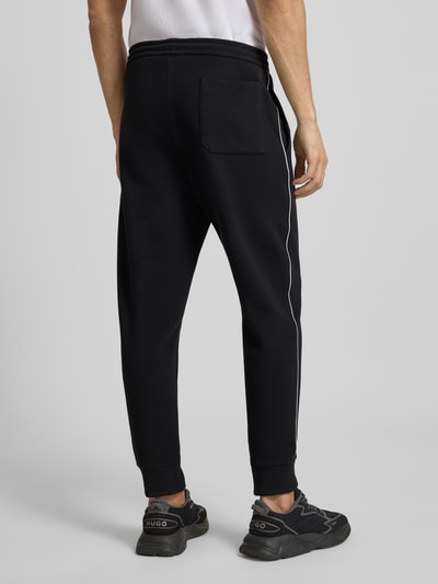 Männermodel draagt Regular Fit Sweat-Anzug aus Baumwoll-Mix Modell 'TRACKSUIT SET' van BOSS Green in uni zwart, Ganzkörperansicht Rückansicht.