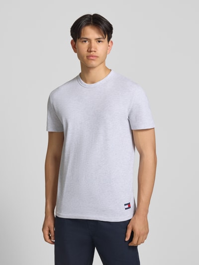 Männermodel trägt Regular Fit T-Shirt aus Baumwoll-Mix von Tommy Jeans in Hellgrau, unifarben, Rundhals, Logo-Stitching, Nahaufnahme Oberkörper.