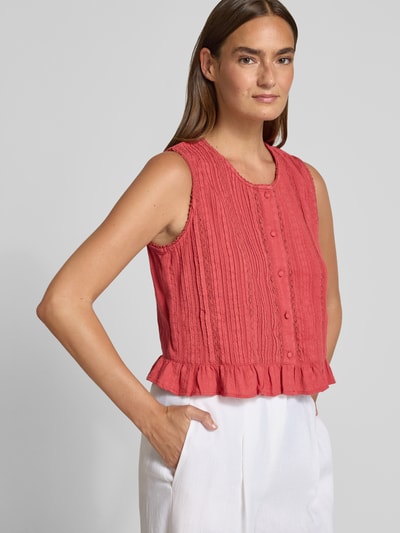 Frauenmodel trägt Blusentop mit Knopfleiste und Häkelspitze von Jake*s Casual, Reine Baumwolle, Regular-Fit, Rundhalsausschnitt, Knopfleiste, Häkelspitze, Rückenlänge bei Größe 36: 46 cm, Rotton, weiße Hose, Struktur-Oberfläche, Ganzkörperansicht von vorne.