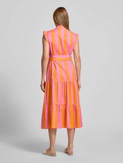 Vrouwenmodel draagt Midikleid met Rüschenbesatz van Christian Berg Woman, puur katoen, getailleerd, opstaande kraag, mouwloos design, tailleband, knoopsluiting, ruglengte maat 36: 116 cm, borstwijdte maat 36: 48 cm, gestreept in roze en oranje, geheel zichtbaar van achteren.