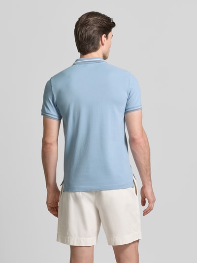 Męski model nosi Slim Fit Poloshirt mit Kontraststreifen od Geox, bawełniany miks, krój slim fit, jasnoniebieski z białymi akcentami, widok całej sylwetki z tyłu.
