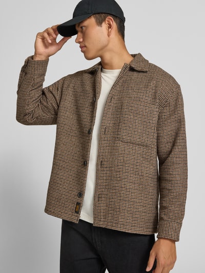 Männermodel trägt Regular Fit Hemdjacke mit Brusttasche Modell 'SOHO OLLIE' von JACK & JONES, braun gemustert, Ganzkörperansicht von vorne. Kontext: Herren Hemdjacke, Kentkragen, durchgehende Knopfleiste, Rückenlänge 71 cm, Schulterbreite 41 cm, Ärmellänge 65 cm.