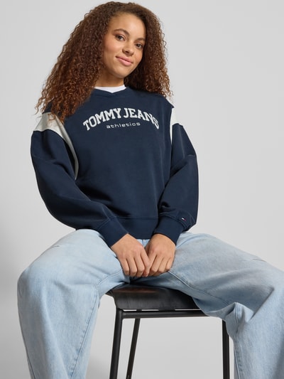 Frauenmodel trägt Boxy Fit Sweatshirt aus Baumwoll-Mix Modell 'VARSITY CREW' von Tommy Jeans in Two-Tone-Optik mit Label-Stitching, gerippten Kontraststreifen und Crew Neck, Sweat-Material, Ganzkörperansicht von vorne.