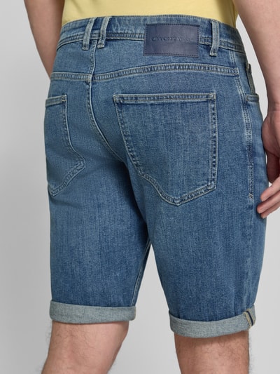 Männermodel trägt Regular Fit Jeans Bermudas aus Baumwoll-Mix von Tom Tailor, Denim-Optik, Label-Patch, 5-Pocket-Design, Ganzkörperansicht Rückansicht.