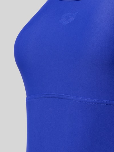 Frauenmodel trägt Slim Fit Badeanzug mit Cut-Out auf der Rückseite von Arena aus Elastischer-Material-Mix in kräftigem Blau, Logo-Detail, verstellbare Spaghettiträger, Nahaufnahme Oberkörper.