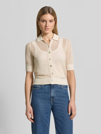 Kobiece modelka nosi Strickjacke aus Leinen mit 1/2-Arm od Christian Berg Woman, kremowy kolor, ażurowa tekstura, krój slim fit, polo kołnierz, pełny zapięcie na guziki, rękaw 1/2, długość tyłu 59 cm, długość rękawa 34 cm, widok całej sylwetki z przodu.