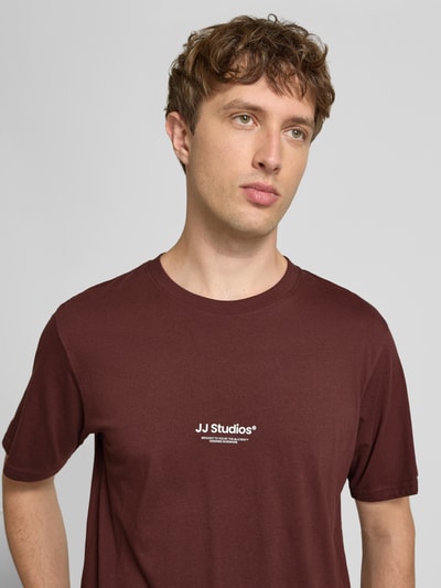 Männermodel trägt Regular Fit T-Shirt mit Logo-Print Modell 'Soho' von Jack & Jones aus reiner Baumwolle in Dunkelrot, Nahaufnahme Oberkörper. Rückenlänge bei Größe M: 61 cm.