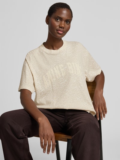 Frauenmodel trägt Oversized T-Shirt mit Logo-Print von Anine Bing aus reiner Baumwolle mit Allover-Animal-Print, Rundhalsausschnitt, Oversized-Fit, helle Farben und sanfte Textur, Ganzkörperansicht von vorne.