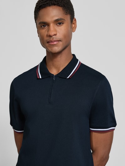 Männermodel trägt Slim Fit Poloshirt mit Kontraststreifen und Reißverschluss von MCNEAL aus Baumwoll-Elasthan-Mix, Nahaufnahme Oberkörper.