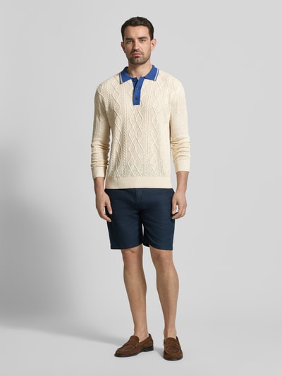 Męski model nosi Strickpullover aus Leinen-Mix mit Polokragen od Gant, beżowy z niebieskim kołnierzem, krój slim fit, przód, zdjęcie całej sylwetki