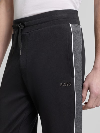 Männermodel trägt Regular Fit Sweatpants aus Baumwoll-Mix von BOSS, Optik: Unifarben, Galonstreifen, Nahaufnahme Hüftbereich.